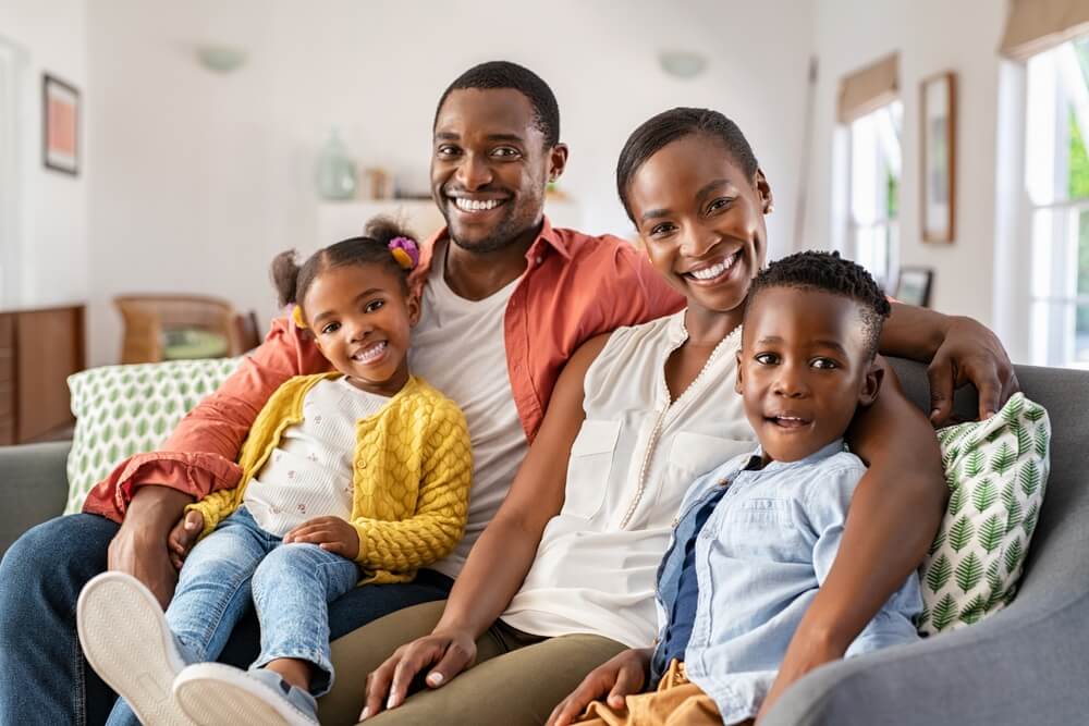 Portrait of happy mature couple with son and daughter relaxing on sofa at home