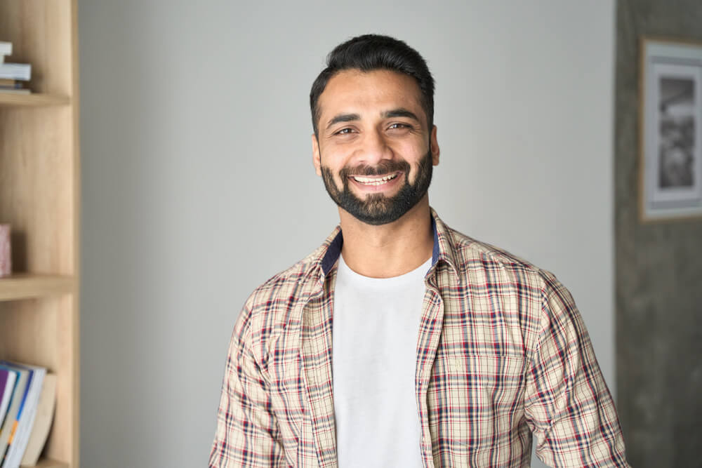 attractive confident indian Hispanic man with toothy smile looking at camera