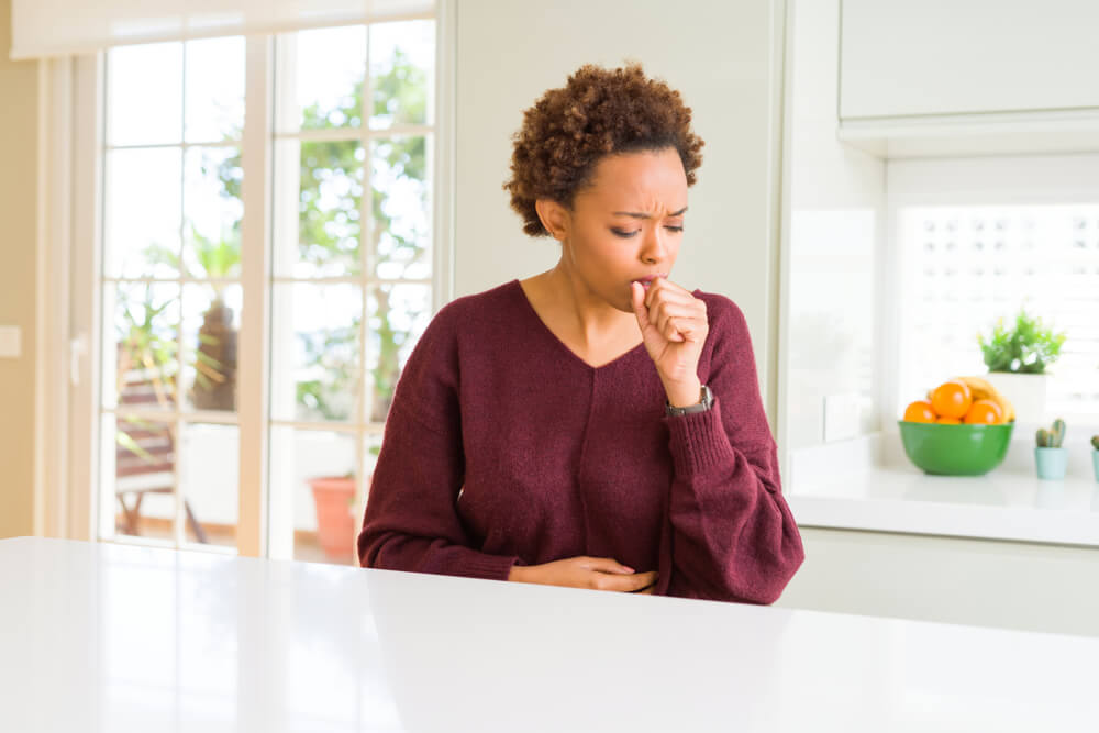 woman at home feeling unwell and coughing