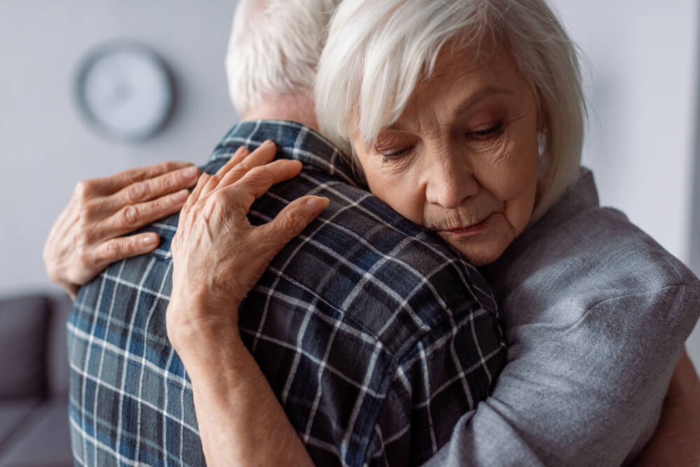 Senior woman with closed eyes embracing husband