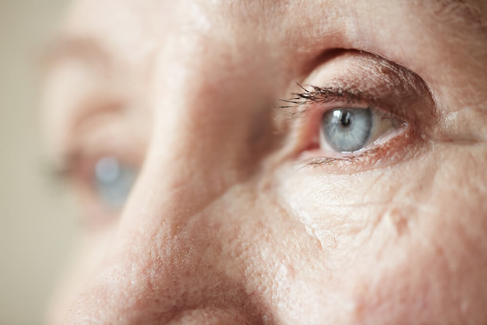 Sad blue-grey eyes of elderly woman