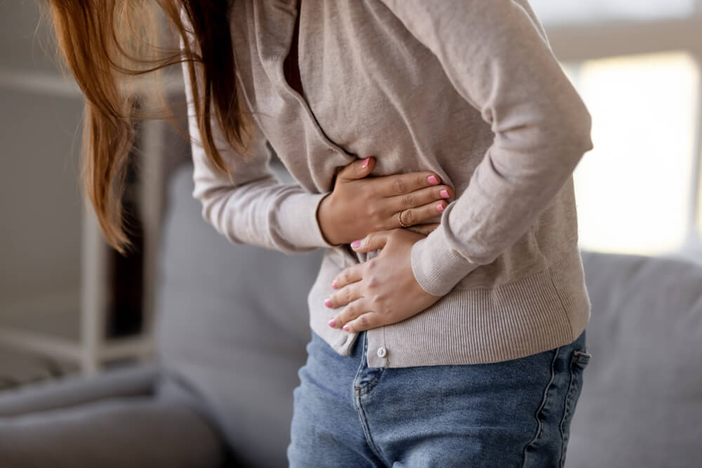 woman holding belly, feeling discomfort