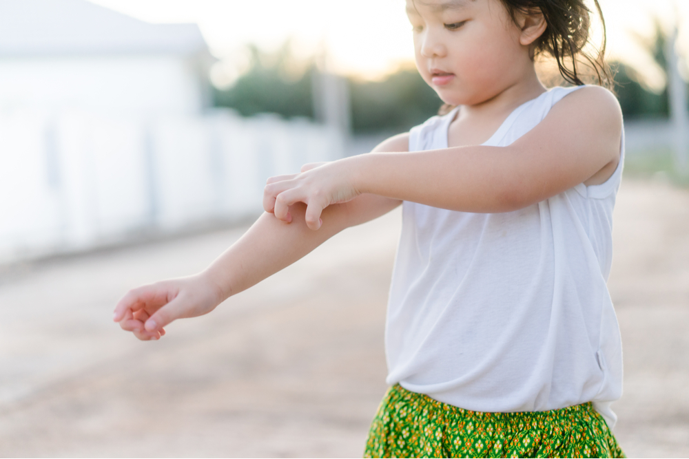 Little girl scratching an itch with hand outdoor