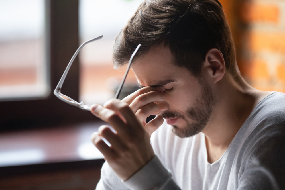 Man holding the bridge of his nose suffering from headaches