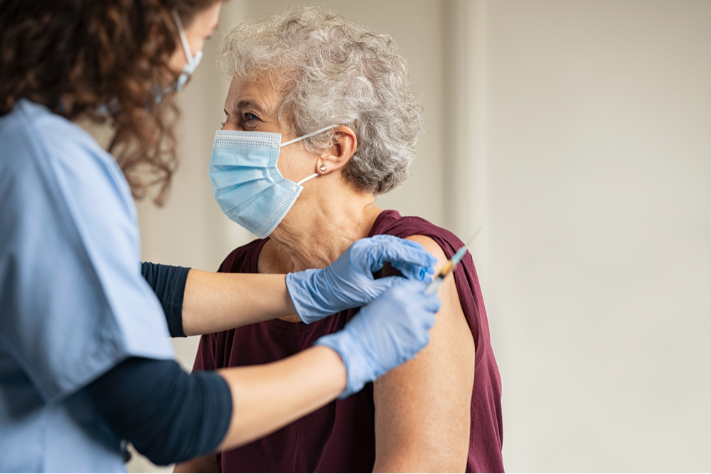 General practitioner vaccinating old patient