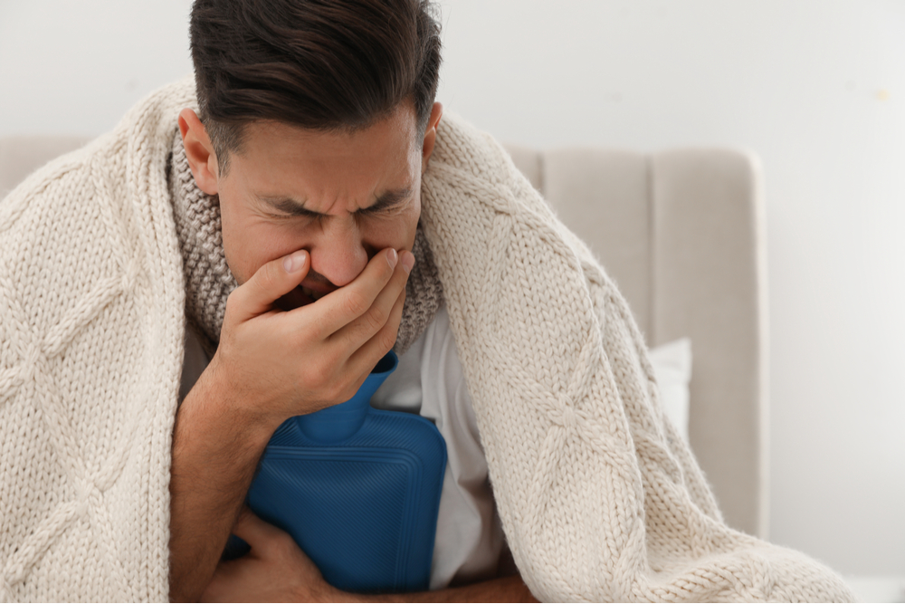 Ill man with hot water bottle coughing