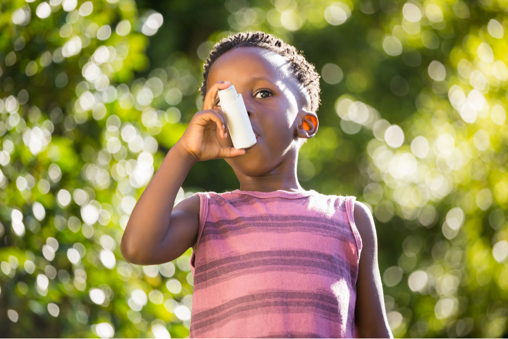 Boy using a asthma inhalator in a park
