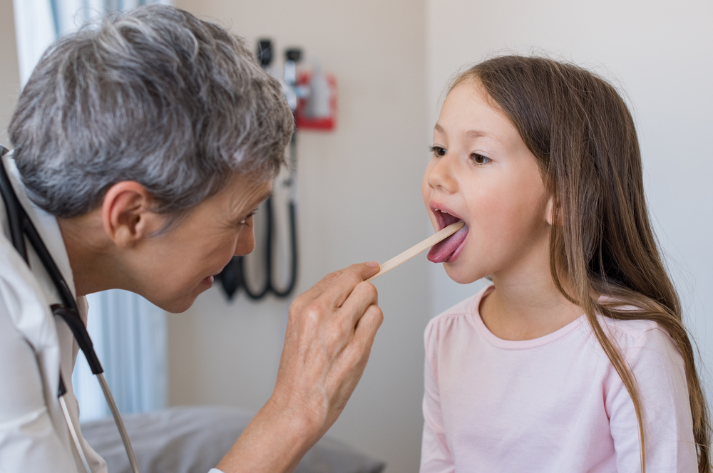 Woman doctor examining little girl mouth