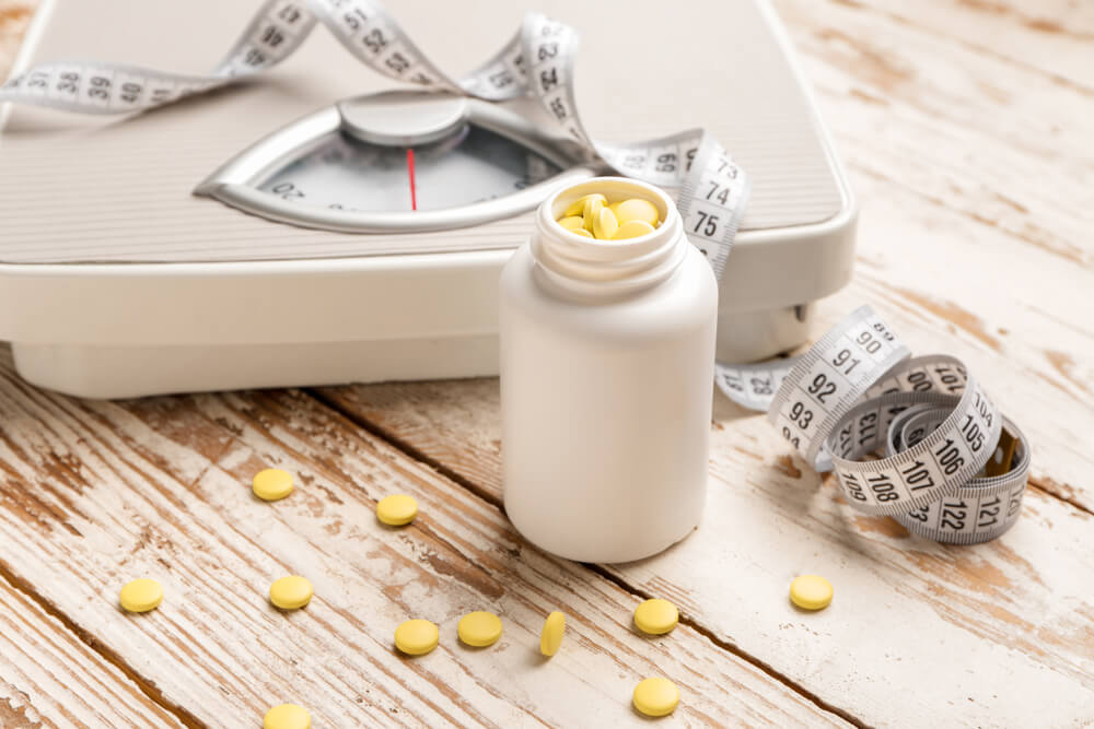 Bottle with weight loss pills, scales and measuring tape