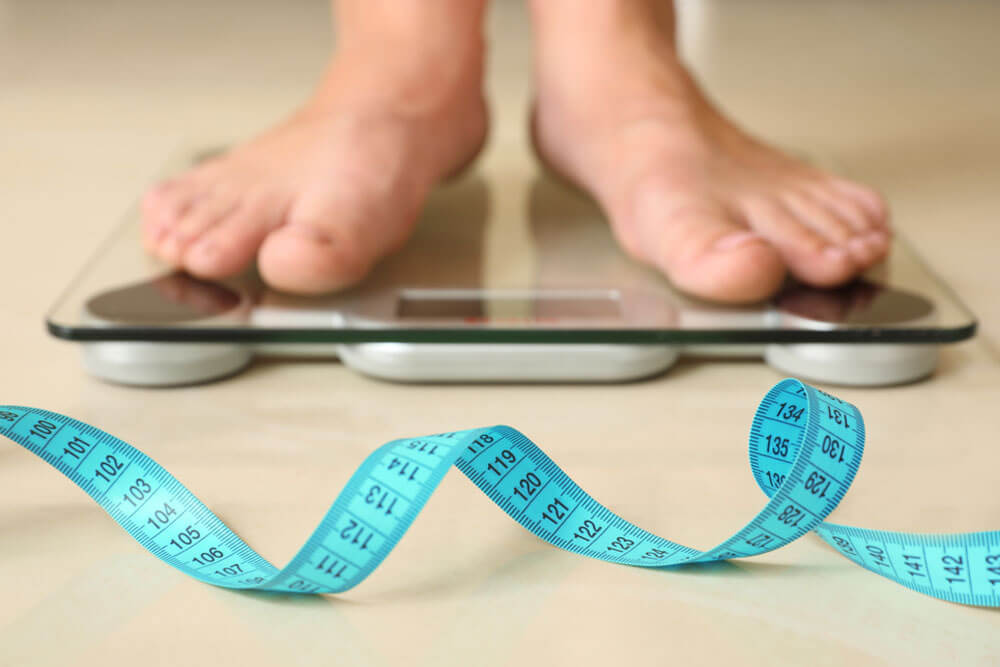 Tape in front of woman standing on floor scales indoors