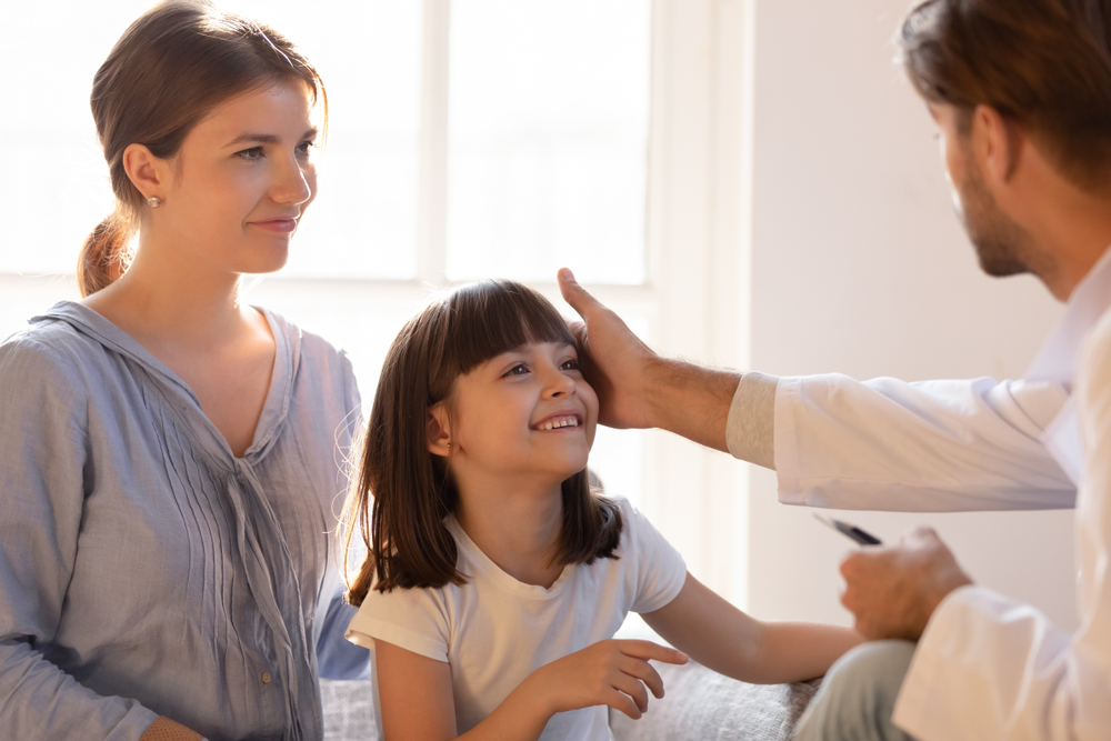 Doctor speaking with a mom and child about Pediatric Primary Care services